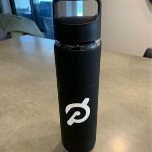 Peleton glass water bottle with rubber casing. New condition. Black and white